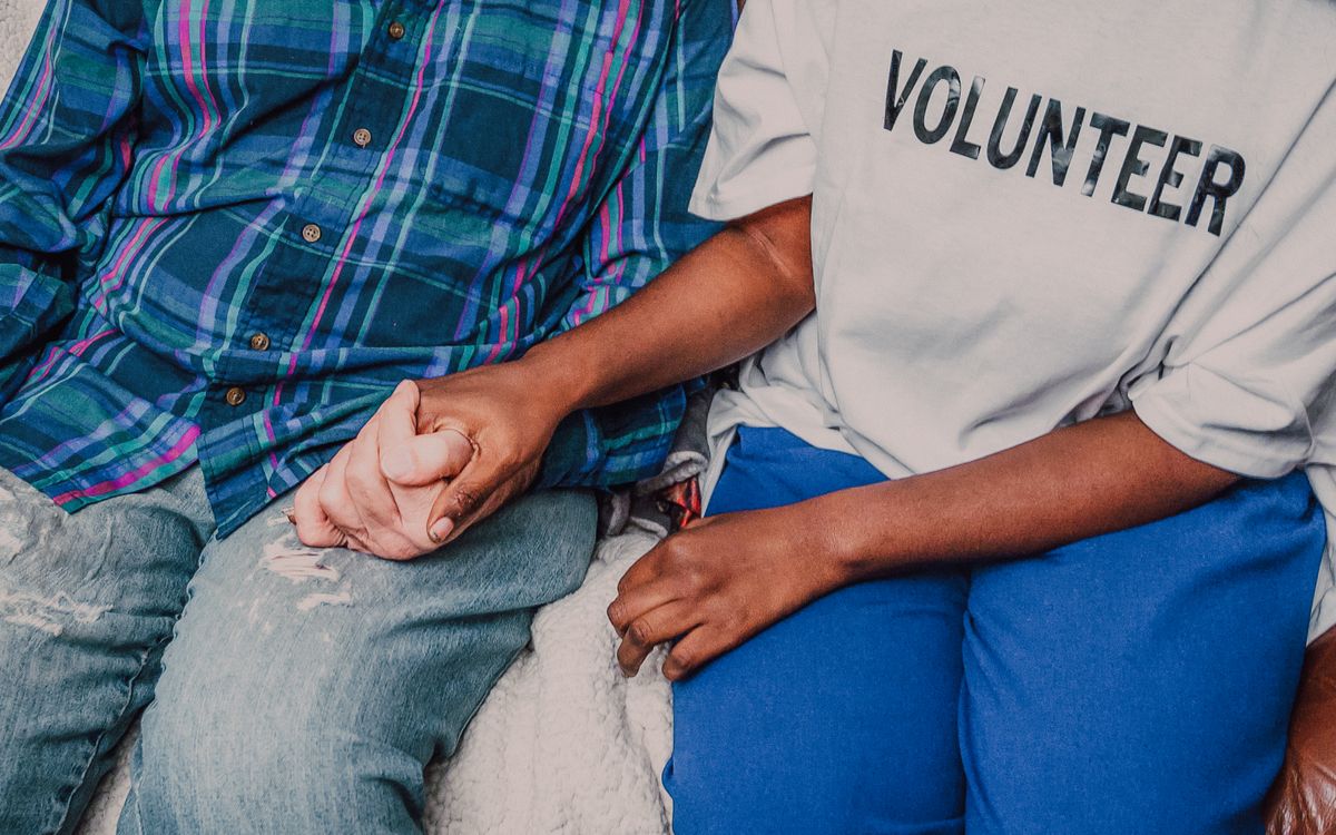 A volunteer holding hands with an older adult